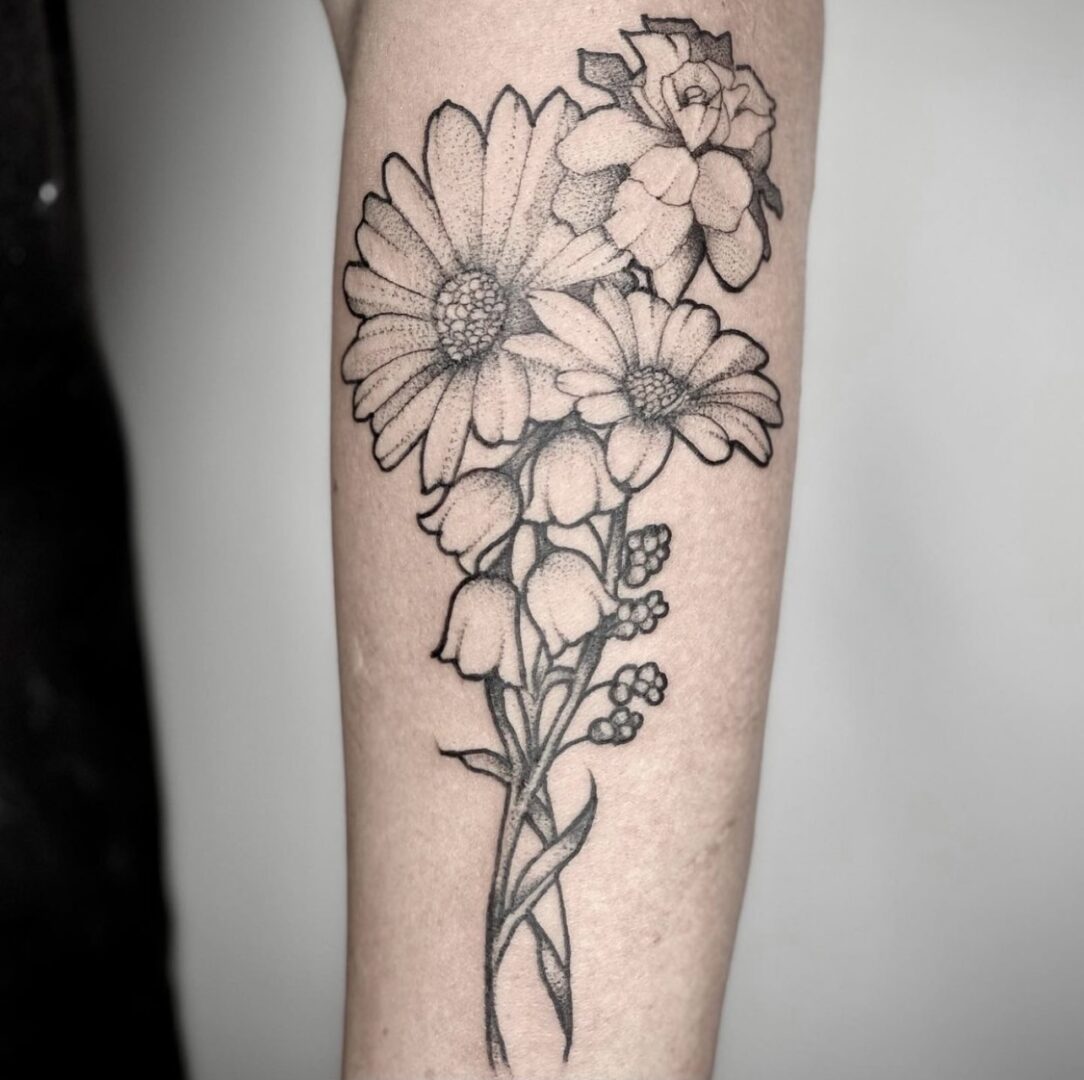 A black and white tattoo of flowers on the arm.