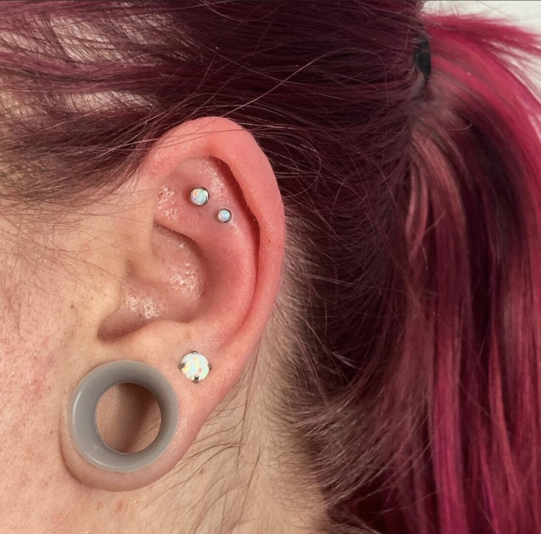 A woman with pink hair and ear piercings.