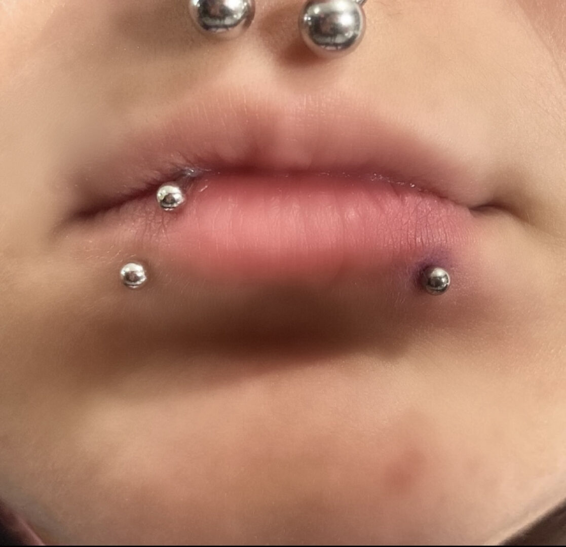A woman with multiple piercings on her lips.