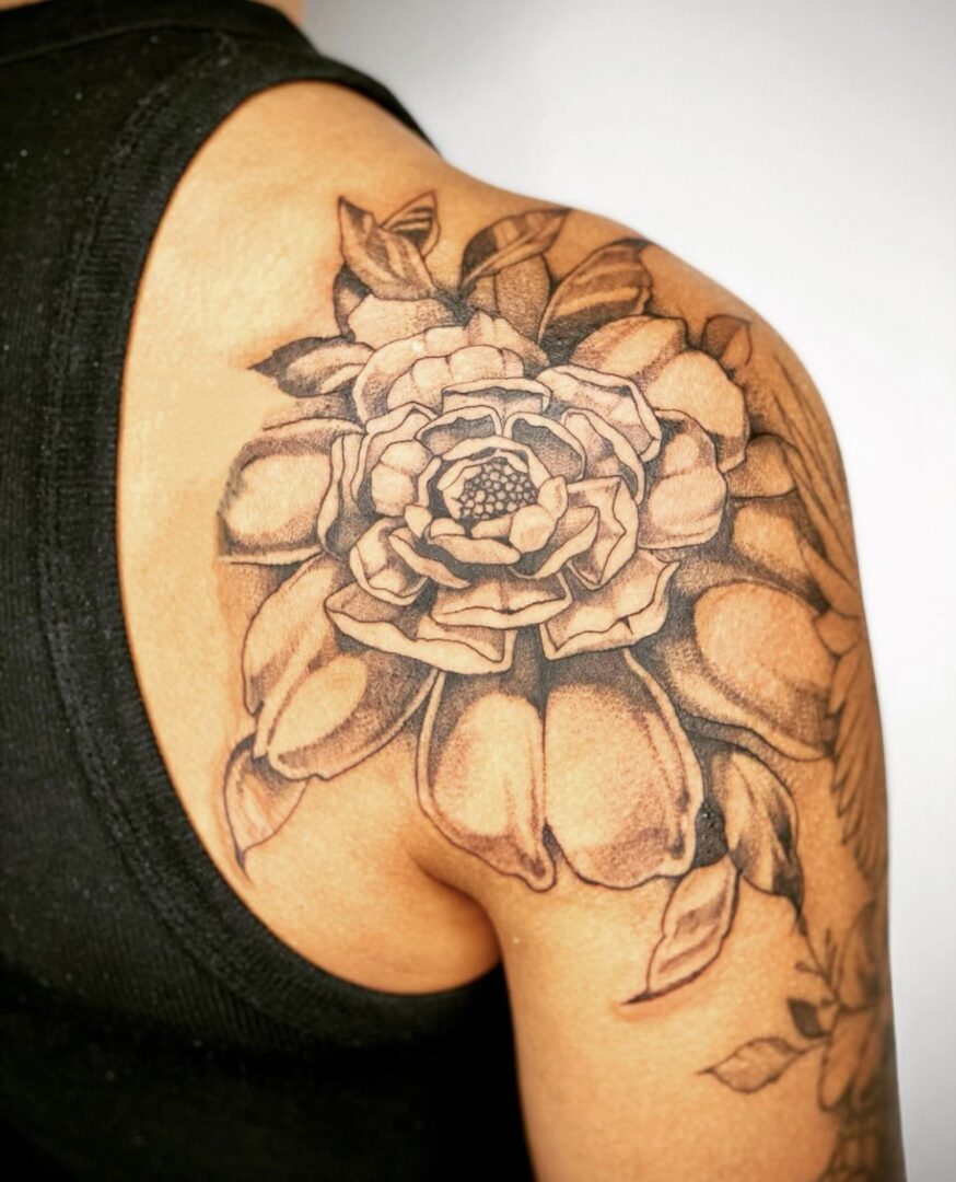 A woman with a tattoo of a flower on her shoulder.