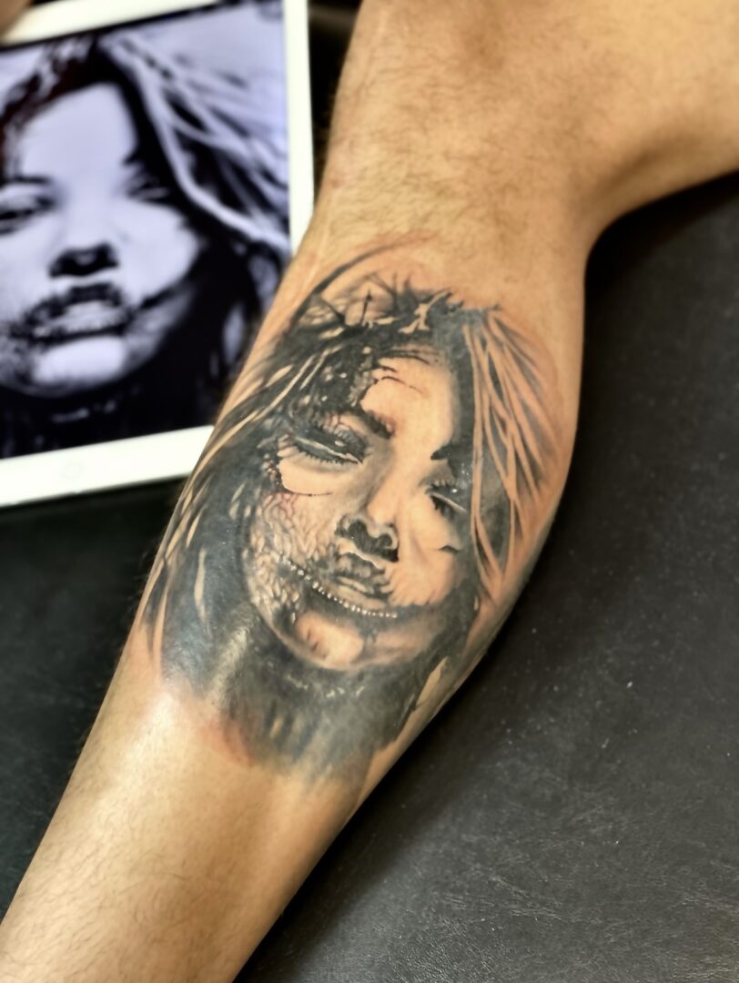 A woman 's face tattooed on the arm of someone.
