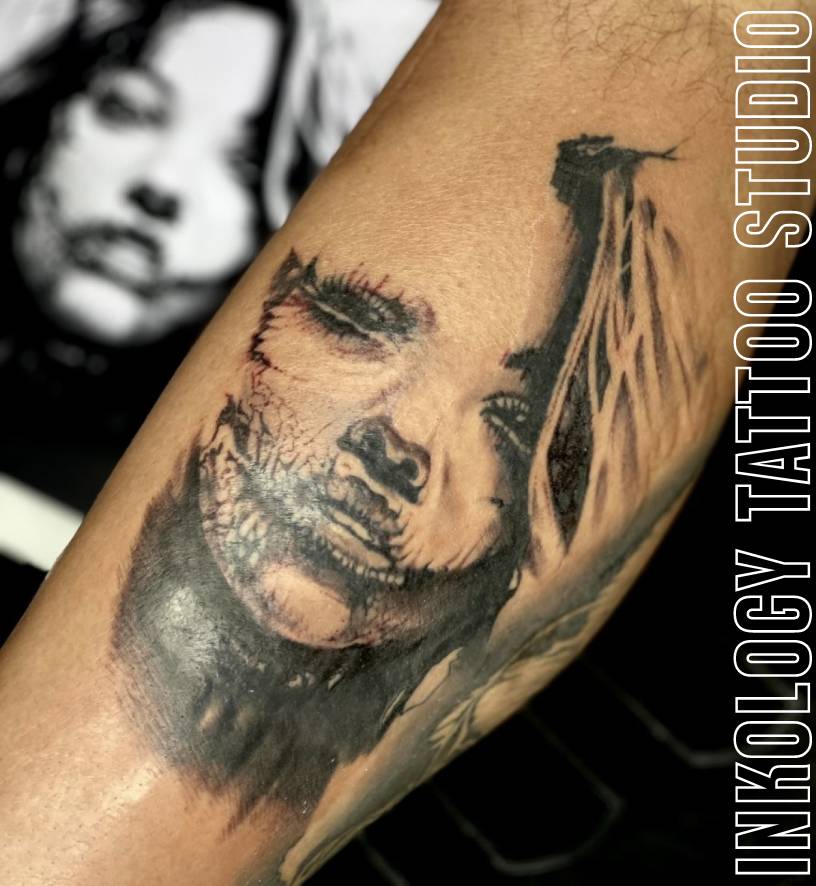 A tattoo of a woman 's face with feathers on it.