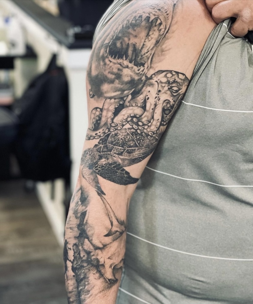 A man with tattoos on his arm and shoulder.