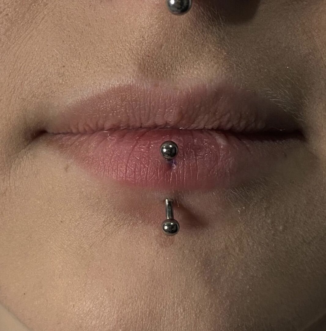 A close up of a person 's lips with piercings