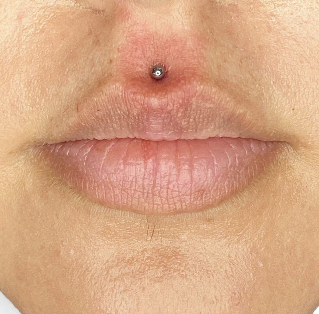 A close up of the lips and nose with a piercing.