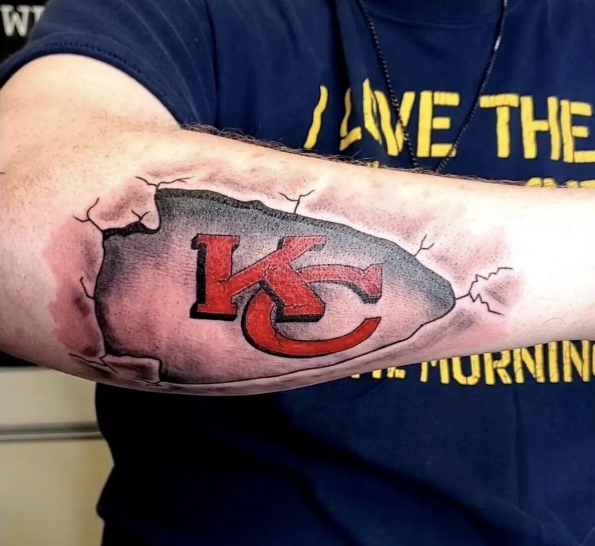 A man with a kansas city chiefs tattoo on his arm.