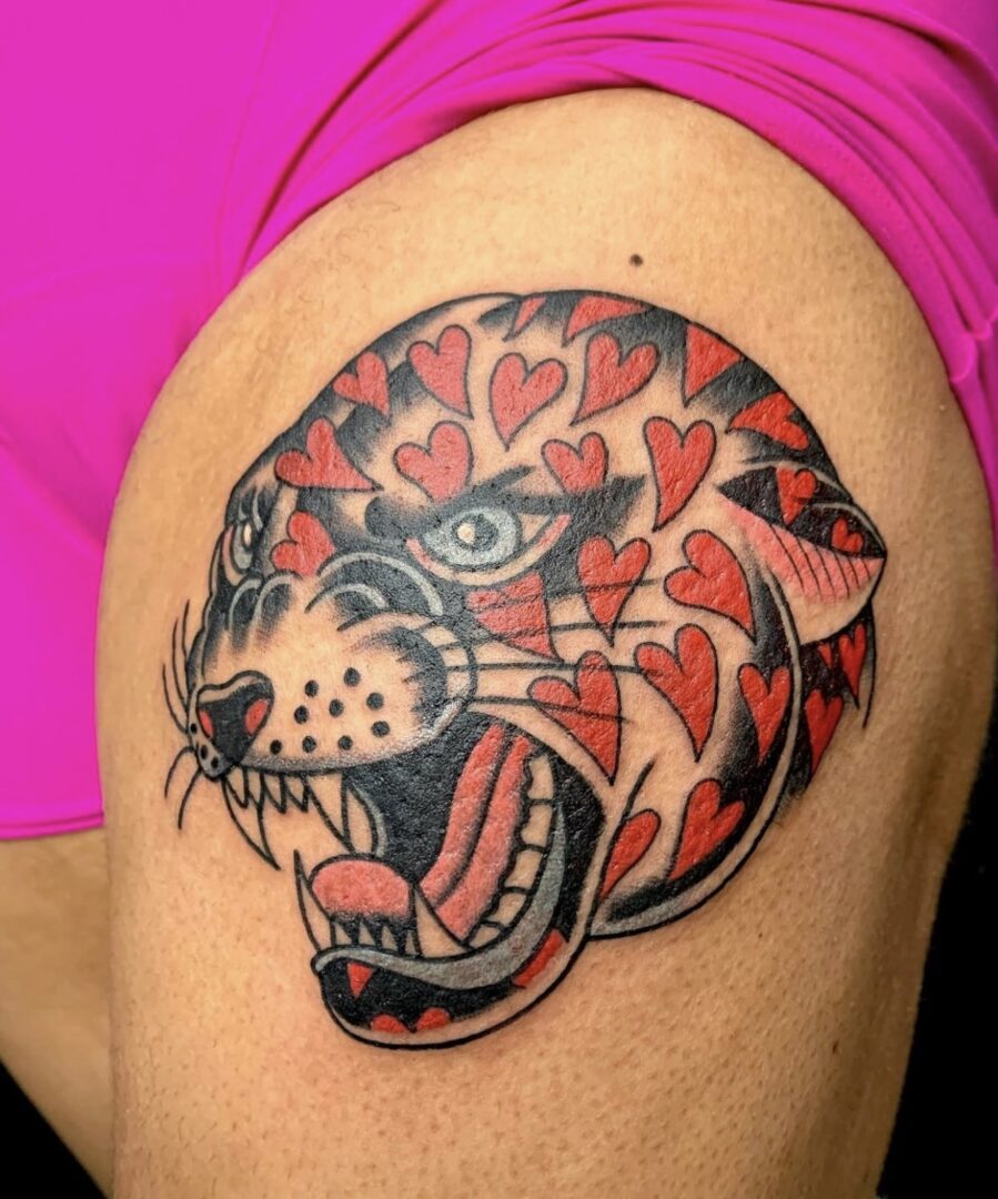 A tattoo of a tiger with hearts on it's face.