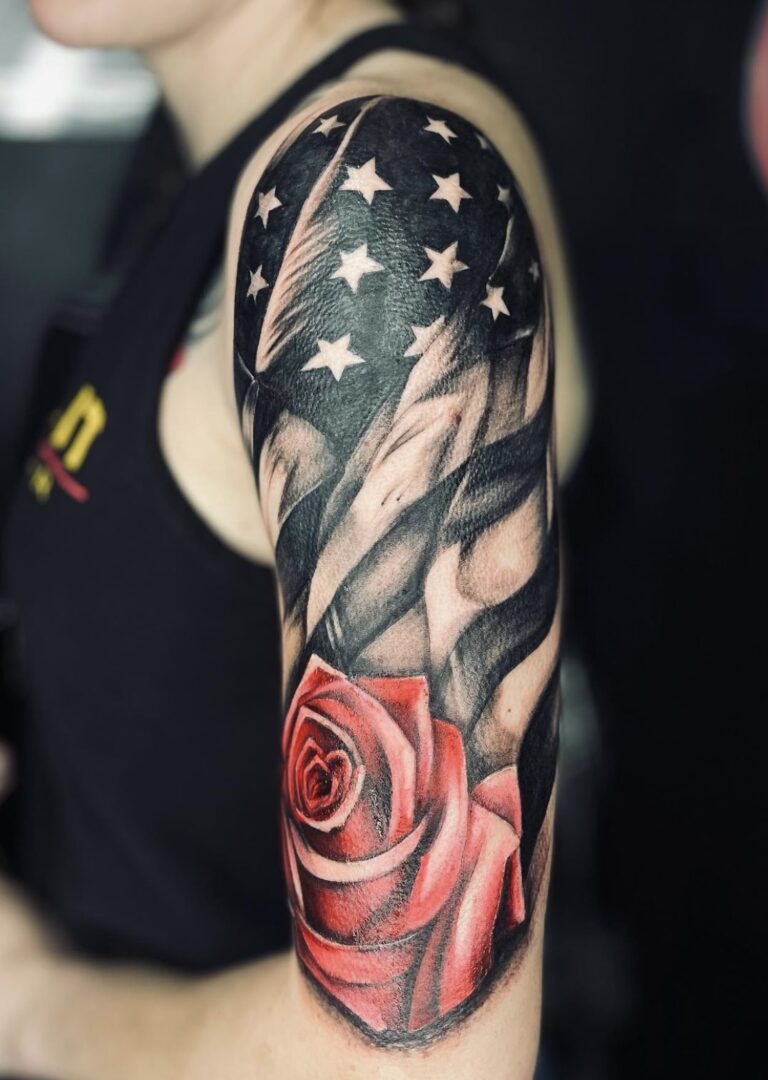 A man with a rose and american flag tattoo on his arm.