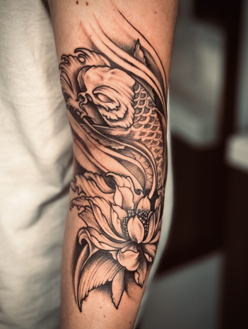 A black and white tattoo of a fish with flowers.