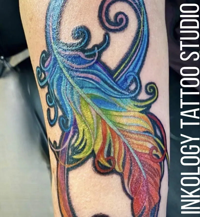 A colorful tattoo of a rainbow colored feather.