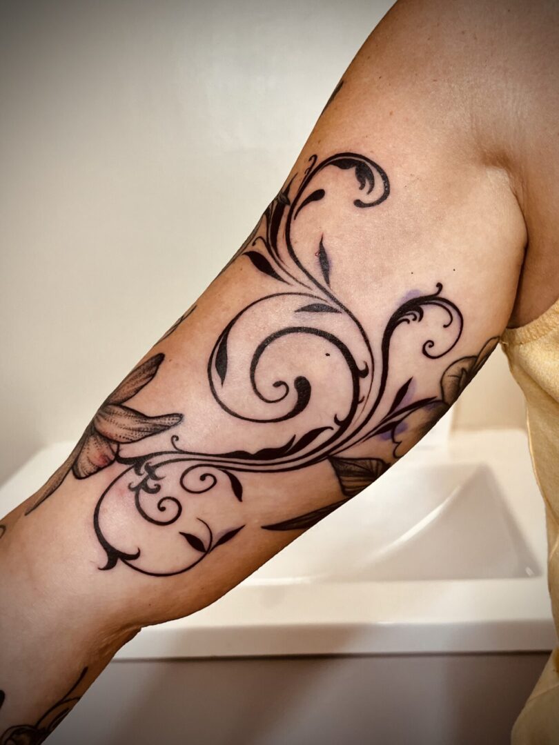A tattoo of a swirly design on the arm.